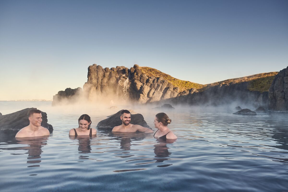 Four adults relaxing in a geothermal hot spring.