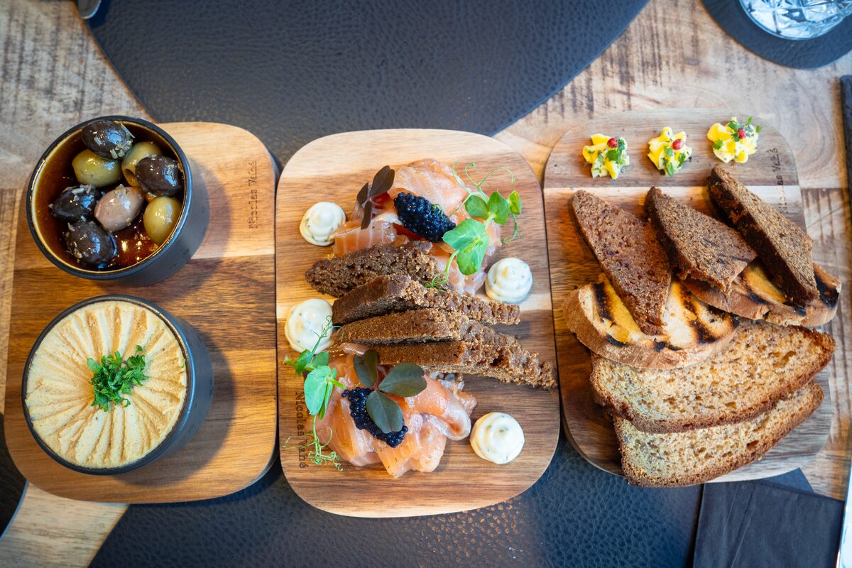 Appetizer platter with salmon, olives, bread, and spreads.