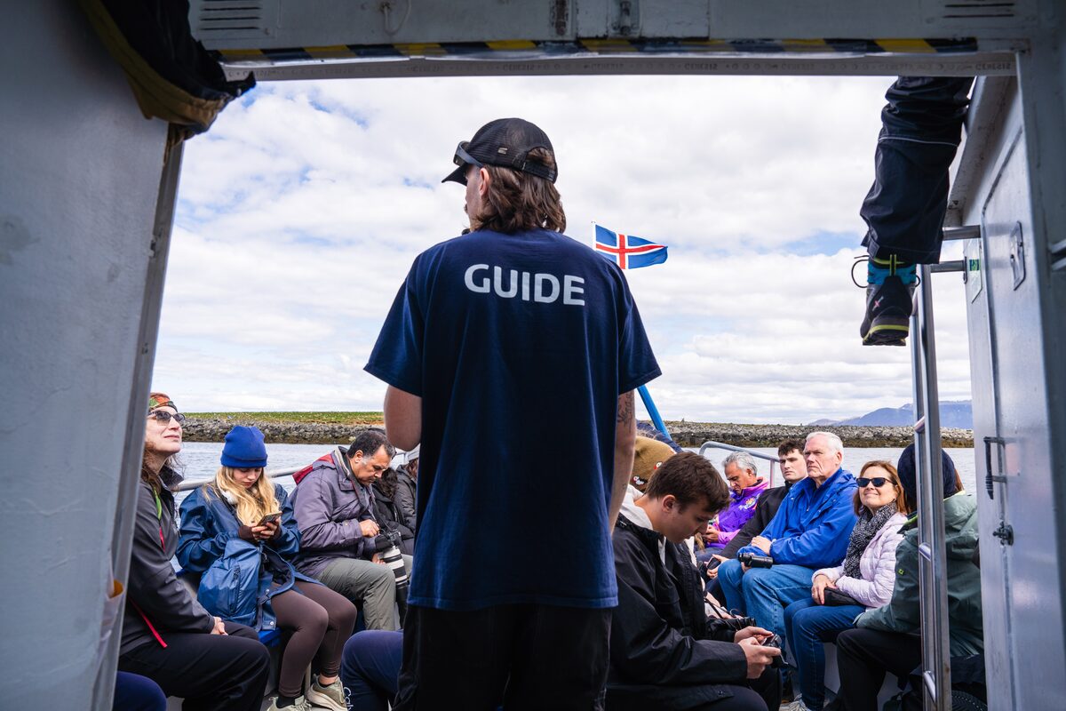 A guide on a boat addressing passengers.
