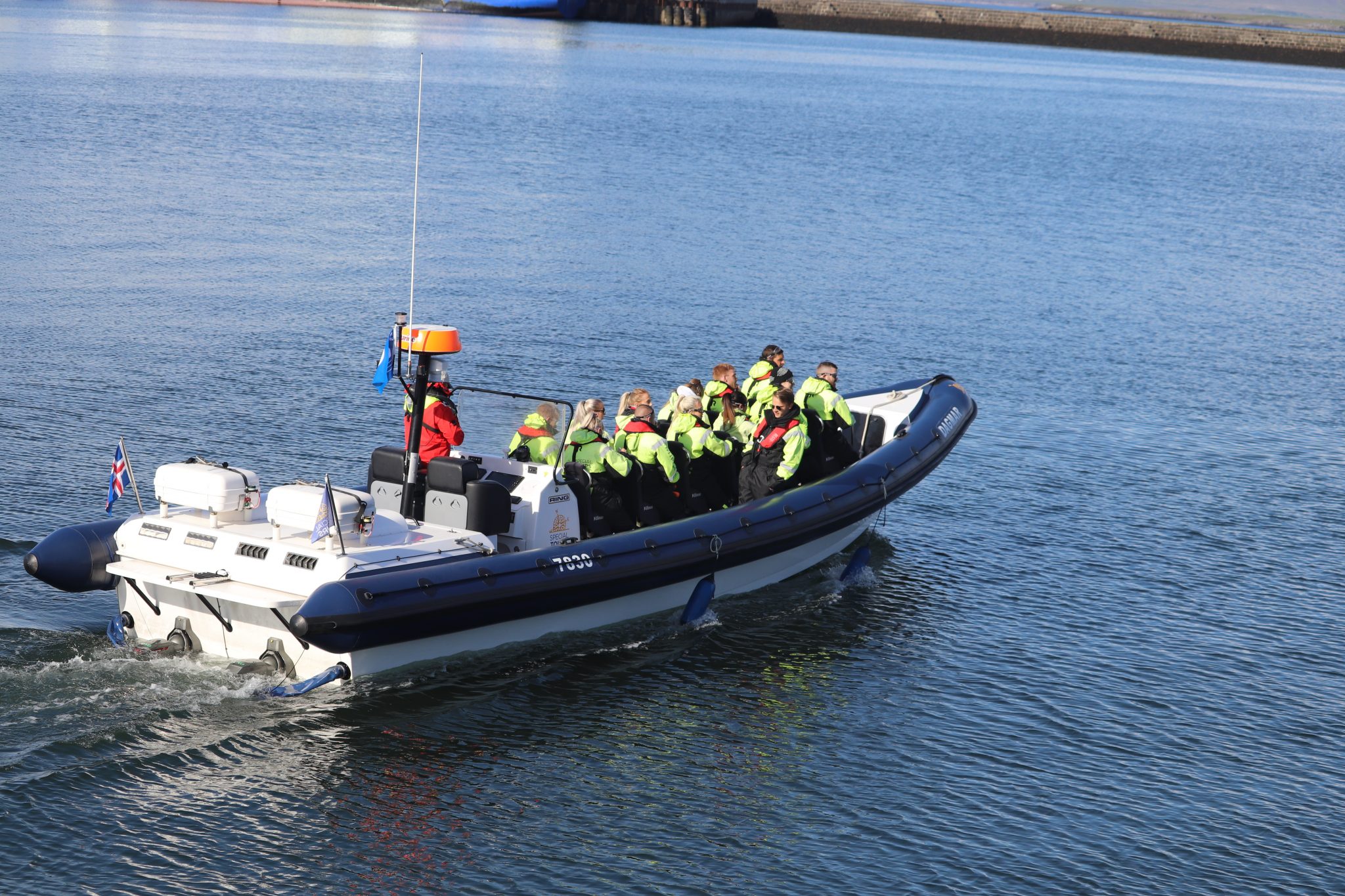 A rigid inflatable boat with passengers in yellow life jackets.