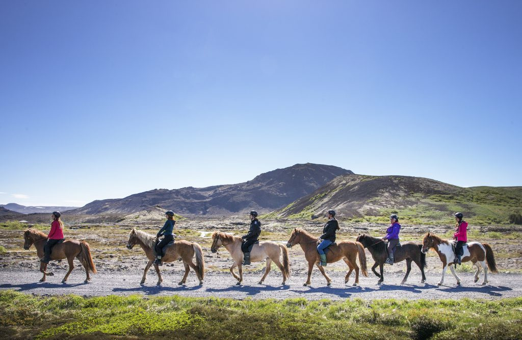 Six people horseback riding through a rocky landscape