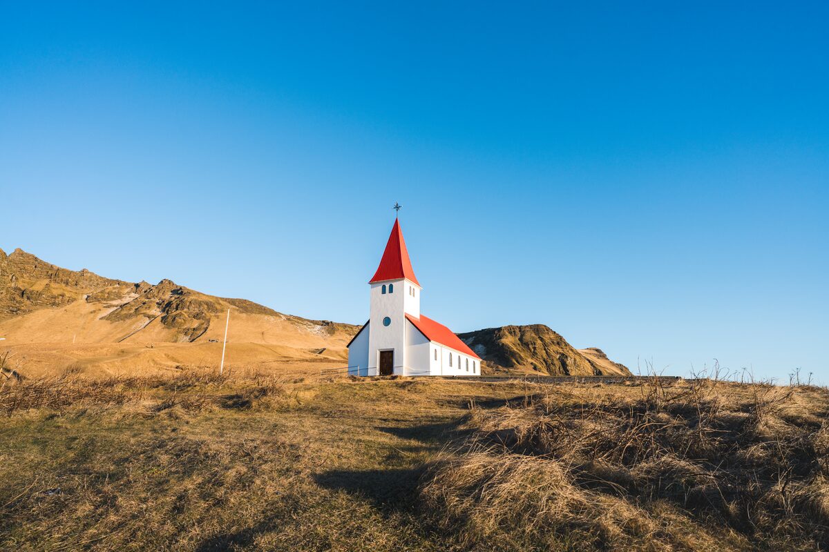 A white church with a red roof stands in Vik, Iceland.