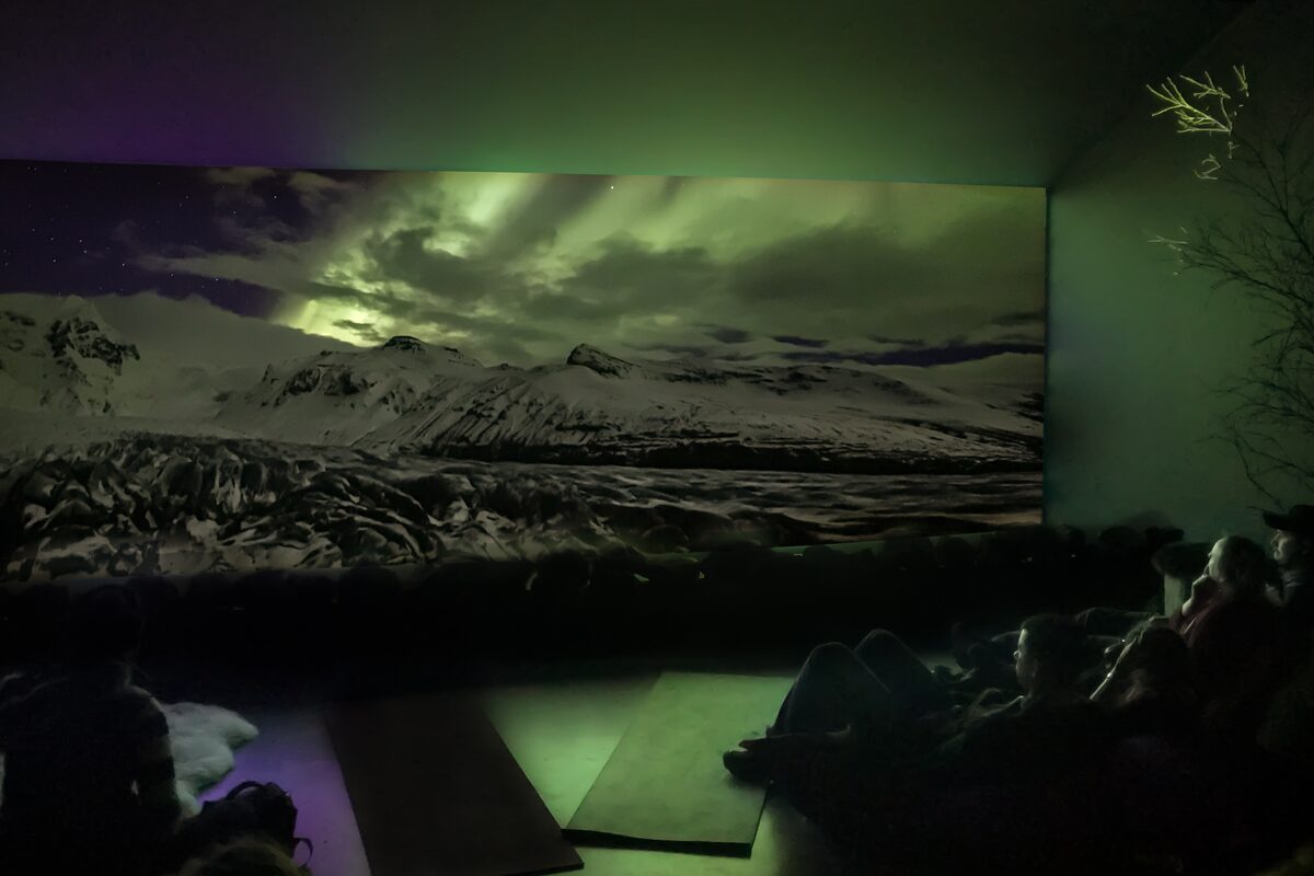 People watching an aurora borealis projection in a theater.