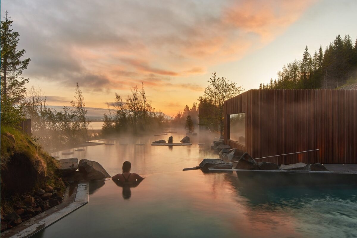 Person relaxing in a hot spring at sunset