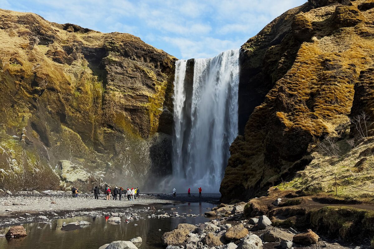 Skogafoss waterfall in Iceland with tourists below.