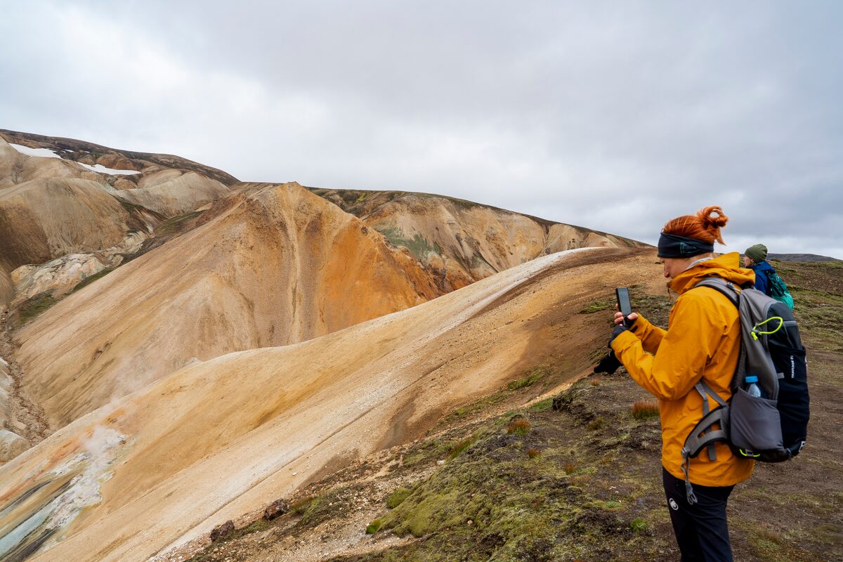 A hiker photographs vibrant rhyolite mountains in Iceland.