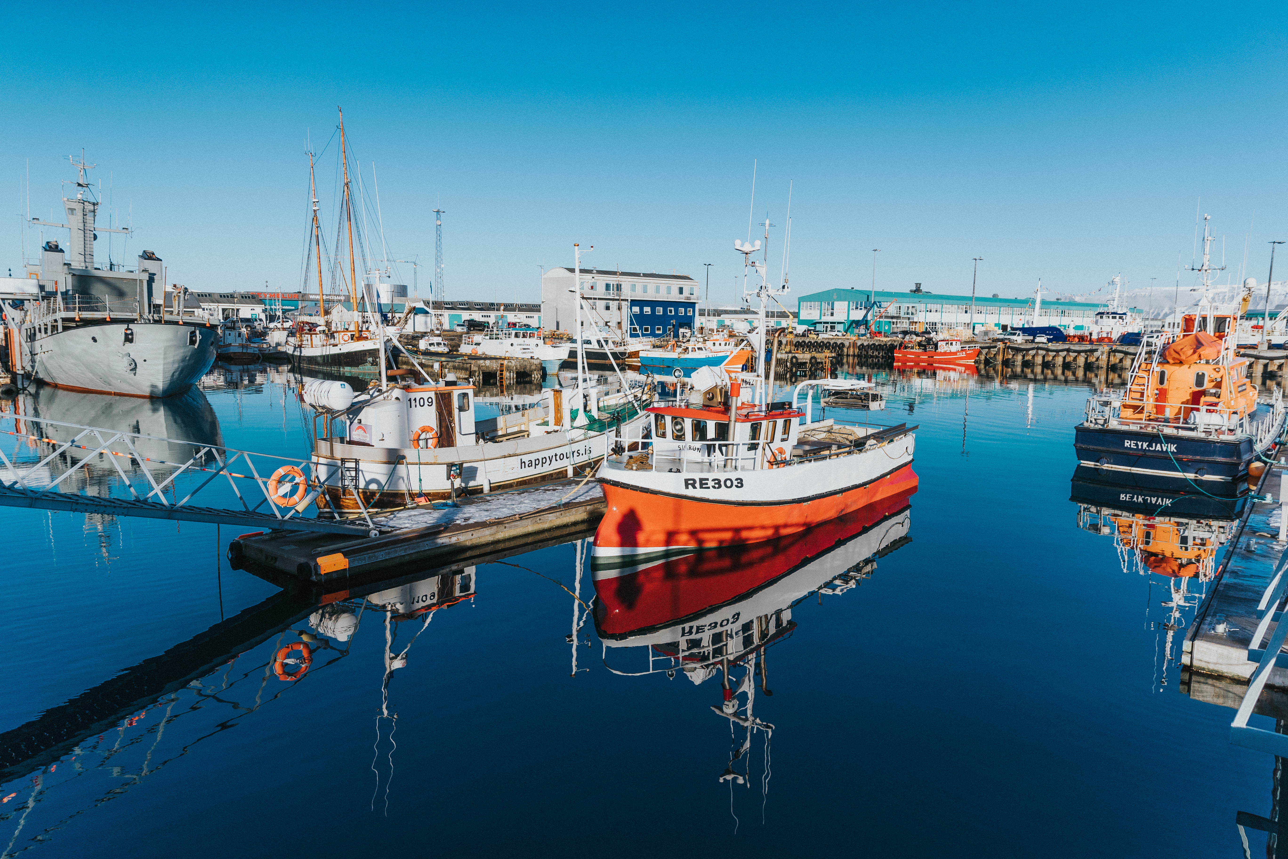 Boats moored in a sunny harbor.